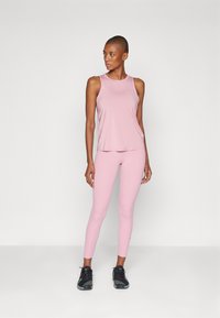 Rosa treningsryggsfor og tights laget av elastisk materiale, med en glatt tekstur og tilpasset design. Svarte treningssko fullfører antrekket.