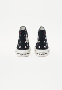 Schwarze High-Top-Sneaker mit pinken Punkten, Gummisohlen und Converse All Star-Logo an der Ferse. Mit weißen Nähten und Schnürsenkeln.