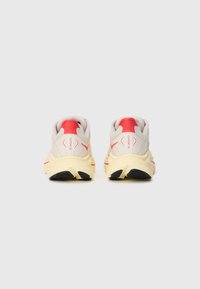 Chaussures de course avec une tige en mesh gris clair, des accents rouges et une semelle texturée jaune. Dotées d'un col rembourré et d'un design épuré.