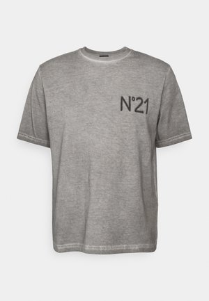 Harmaa lyhythihainen T-paita haalistuneella ilmeellä ja musta "N°21" painettuna rinnassa, yhdistettynä mustiin housuihin ja mustiin tennareihin.