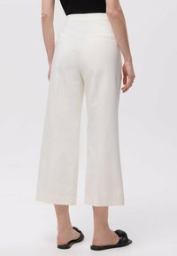 Pantaloni culotte in tessuto crema, con vita alta, tasche laterali e gambe larghe. I bordi sono rifiniti in modo pulito e dritto.