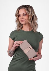 Beige wallet with a textured vertical band, accentuated by a zigzag pattern and a small logo. The material appears smooth and sturdy.