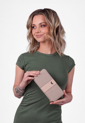 Beige Geldbörse mit einem strukturierten vertikalen Band, akzentuiert durch ein Zickzackmuster und ein kleines Logo. Das Material wirkt glatt und robust.