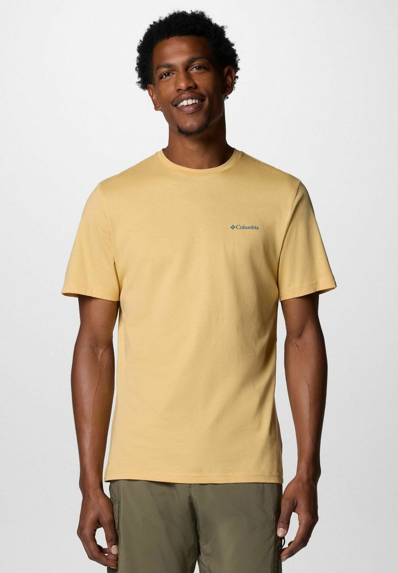 Kurzärmliges T-Shirt mit Rundhalsausschnitt aus leichtem gelben Baumwollstoff, mit Columbia-Logo in Türkis auf der linken Brust. Einfaches Design, leichtes Material.