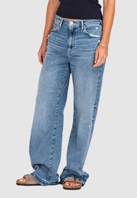 Szerokie, jasnoniebieskie dżinsy z przetarciami, pięcioma kieszeniami, zapięciem na guzik z przodu i postrzępionym dołem.