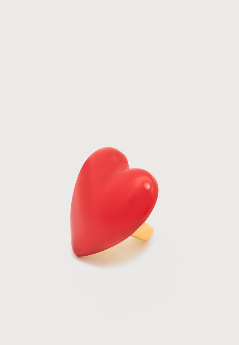 Δαχτυλίδι σε σχήμα κόκκινης καρδιάς με λεία, ματ επιφάνεια και χρυσοκίτρινη μπάντα. Το σχέδιο διαθέτει στρογγυλεμένες άκρες και έντονο περίγραμμα καρδιάς.