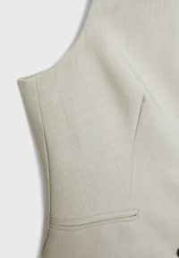 Ljust beige skräddarsydd väst med en slät textur, med en subtil tygväv, sid söm och en enda passpoal fickdetalj.