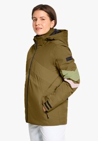 Olivgrüne Jacke mit Kapuze, mit diagonalen Nähten, mehrfarbigen Akzenten an den Ärmeln und Reißverschlusstaschen. Strukturiertes Material, modernes Design.