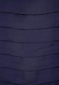 Tela azul marino con pliegues horizontales que crean una apariencia texturizada y en capas. Superficie lisa con un diseño suave y fluido.