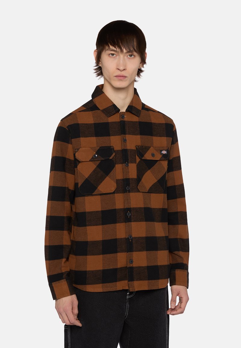 Brun og sortternet skjorte med lange ærmer, knaplukning foran og to brystlommer. Fremstillet af stof med flanneltekstur.