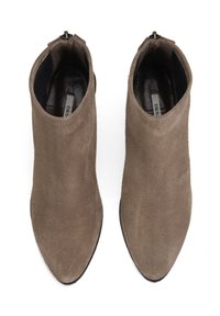 Hnědé semišové kotníkové boty s špičatou špičkou, se zipem na zadní straně a hladkým vnitřním podšívem. Plná podrážka a strukturovaný povrch.