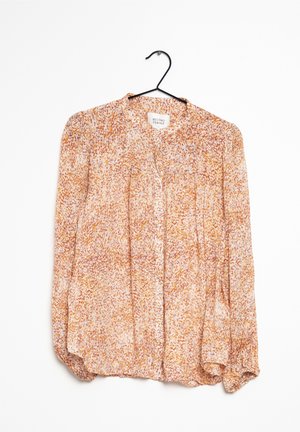 Blusa leggera a maniche lunghe con chiusura frontale con bottoni. Decorata con motivi arancioni e crema, presenta una consistenza morbida e leggermente trasparente.