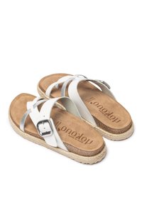 Witte sandalen met kruisbanden en zilveren accenten, kurken voetbed en geweven jute zool. Voorzien van een metalen sluiting.