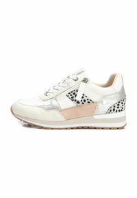 Zapatilla con una parte superior blanca, acentos plateados y beiges, y lunares negros. Presenta cordones y un zipper lateral para facilitar su uso.