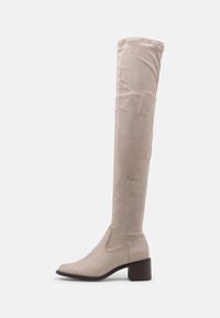 Botas beige hasta la rodilla, hechas de suave ante, con punta redonda y un tacón grueso y texturizado. Diseño elegante y liso con mínima costura.