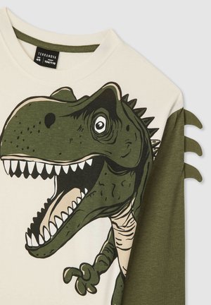 T-shirt per bambini con base crema e maniche verdi; presenta una grande grafica di un dinosauro con denti e occhi dettagliati.