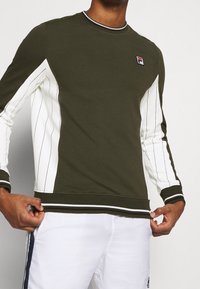 Sudadera verde oliva con mangas rayadas en blanco en contraste, cuello acanalado y puños, que presenta un pequeño logo en el pecho.