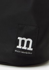 Black fabric bag featuring a rectangular label with white text, "marimekko" and a stylized "m," stitched at the corner.