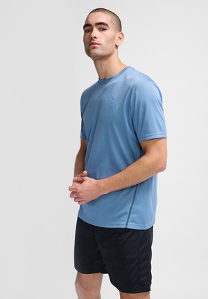 T-shirt de sport à manches courtes, bleu clair, avec un col rond et un détail de logo subtil, associé à un short noir. Texture lisse et design ajusté.