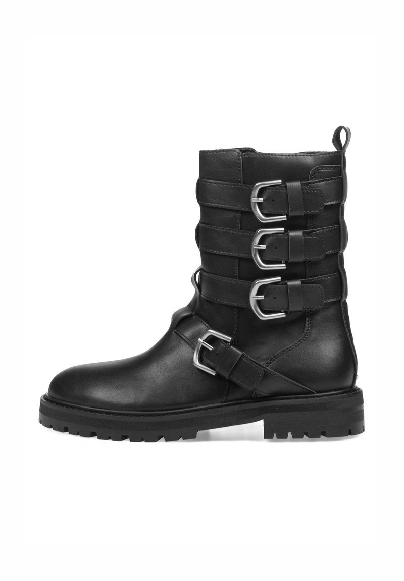 Bota negra de cuero hasta el tobillo con cuatro correas anchas y adornos de hebilla de plata. Presenta una suela de goma resistente y una cinta en la parte posterior para facilitar el calzado.