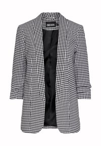 Blazer en blanco y negro con diseño de espiga, abertura frontal, hombros estructurados y mangas enrolladas, forrado con tela negra.