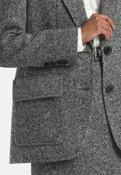 Šedý vzorovaný vlněný blazer s klopovým límcem, dvěma knoflíky a přední kapsou. Texturovaná tkanina s kontrastními tečkovanými detaily.