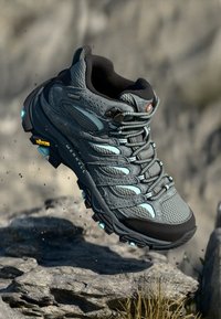 Grå hiking boots med pustende mesh og syntetisk overdel, med lyseblå aksenter, robust såle og Vibram-merke.