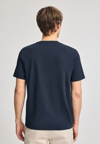 T-shirt bleu marine à manches courtes avec un col rond, fabriqué en tissu doux, avec un design uni et une coupe décontractée.