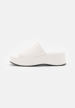 Hvid platformsandal med tyk sål og åben tå, vist fra siden på en ensfarvet hvid baggrund.