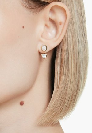 Uhani v zlati barvi z jasnim osmokotnim draguljem na vrhu in trikotnim draguljem spodaj, oba z brušenimi površinami.