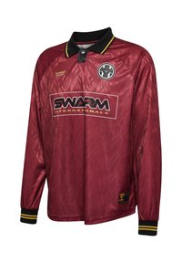 Tumepruun pikkade varrukate sportlike jersidega särk musta krae, kollased triibud mansettidel, "SWARM Internationals" logo ja ümmargune embleem rinnal.