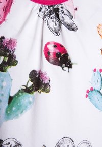 Bavlněná tkanina s barevnými květinovými a hmyzími vzory, včetně berušek a kaktusů, s růžovým výstřihem.