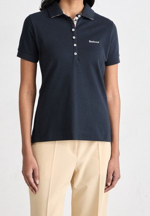 Granatowa koszulka polo z kołnierzykiem, krótkimi rękawami i plisą na guziki. Na piersi znajduje się biały napis "Barbour", a kołnierzyk ma wzorzyste wnętrze.
