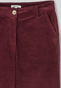 Pantalons en velours côtelé à jambes larges de couleur bordeaux, avec des côtes verticales, un bouton frontal unique et deux poches latérales.