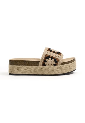 Sandalia de plataforma con suela beige tejida y tiras de ganchillo con un diseño de cuadros en marrón, crema y negro.