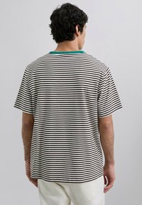 Camiseta a rayas en color blanco roto y marrón oscuro con un cuello verde. Mangas cortas, corte relajado, con dobladillo recto y textura de tela suave.