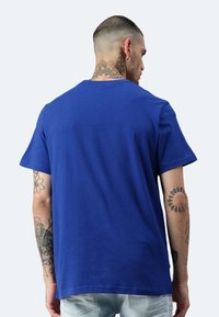 T-shirt in cotone blu royal con maniche corte, scollo rotondo classico e orlo dritto. Presenta cuciture visibili e una texture liscia.