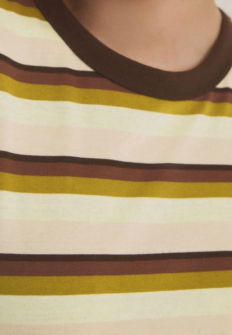 Gros plan sur un col de chemise avec des rayures horizontales marron, jaune moutarde, crème et beige.