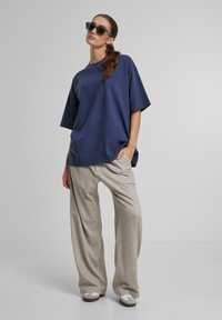 Marineblå oversized t-shirt med korte ærmer, parret med lysegrå fløjlsbukser med bred ben og grå slip-on sko. Tekstureret stof med en afslappet pasform.