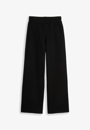 Schwarze weite Hose mit elastischem Bund und subtil strukturiertem Muster, flach auf weißem Hintergrund präsentiert.