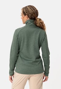Giacca in fleece verde, testurizzata, con colletto alto, maniche lunghe e motivo sottile. Presenta una vestibilità comoda e un orlo curvo.