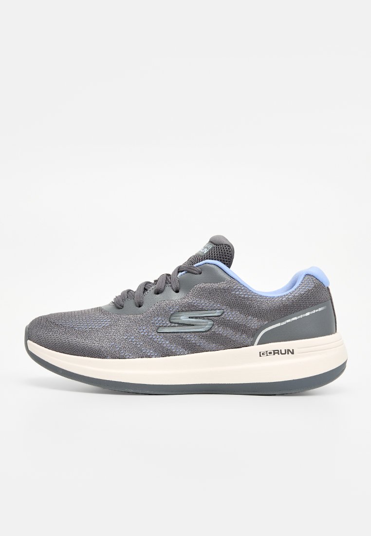Zapatilla deportiva gris con parte superior de malla, acentos en azul claro, entresuela blanca gruesa y suela negra. Presenta un logo en el costado y en el talón.