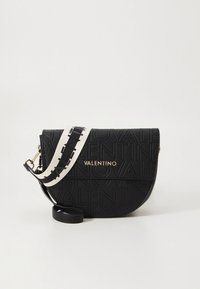 Černá kožená kabelka přes rameno s embosovaným logem, zlatým názvem značky a kontrastním bílým popruhem s černými detaily.