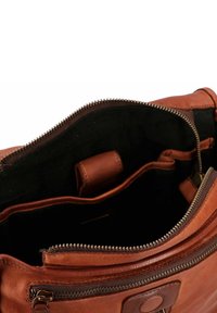 Borsa a spalla in pelle marrone con chiusura zip, dotata di un interno morbido e con texture e due tasche aperte. Vano con zip visibile.