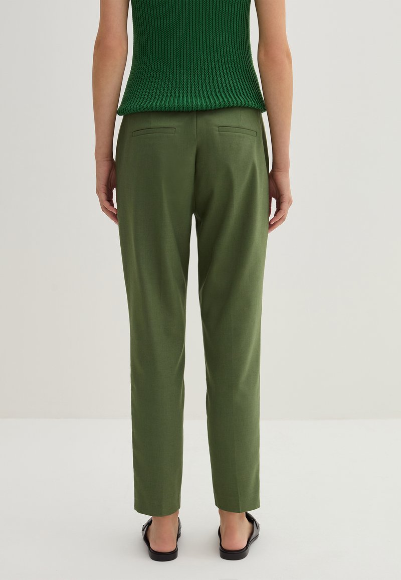 Grüne maßgeschneiderte Hose aus strukturiertem Stoff, mit slim fit, seitlichen Taschen und einem glatten Abschluss an den Säumen.