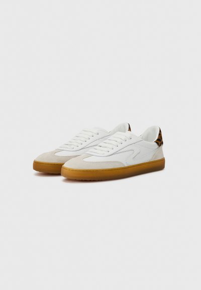 Vit och beige sneaker med överdel av mocka och läder, snörning och en gummisula, med en leopardmönstrad detalj vid hälen.