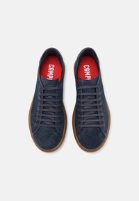 Sneaker in suede blu navy con punta arrotondata, lacci piatti e suola in gomma naturale. Le solette rosse presentano la parola "CAMPEL" in bianco.