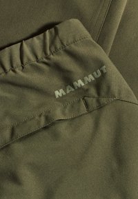 Olijfgroen stof met een gladde textuur, met een geraffineerde tailleband en een gestikte zak. "MAMMUT" logo in lichtgroene kleur geperst.