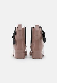 Bottes de cheville en cuir verni rose avec des panneaux élastiques noirs sur les côtés et des accents en nœud. Design sans lacets avec des semelles en caoutchouc texturé pour une bonne adhérence.