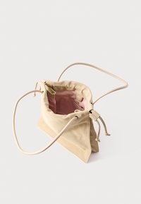 Μπεζ σουέντ τσάντα ώμου με κορδόνι, μακριές τιράντες και εσωτερική επένδυση σε ανοιχτό ροζ χρώμα, σε άποψη από πάνω που δείχνει το ανοιχτό κύριο διαμέρισμα.